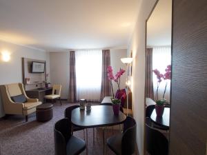 ein Hotelzimmer mit einem Tisch, Stühlen und einem Schreibtisch in der Unterkunft 24Hours-Apartment in Wien