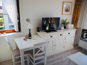 een woonkamer met een tafel en een tv op een kast bij Entennest in Wenningstedt