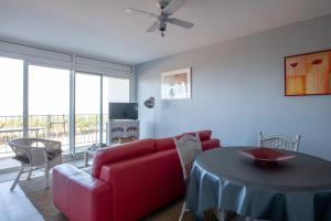 a living room with a red couch and a table at Appartement face mer et aux pins in Saint-Brevin-les-Pins