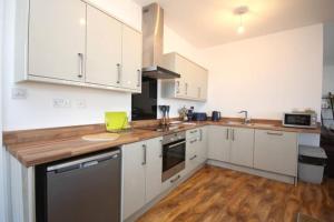 eine Küche mit weißen Schränken und einem Holzboden in der Unterkunft Modern, Luxurious Two Bedroom Apartment in Great Yarmouth + 8 Fotos