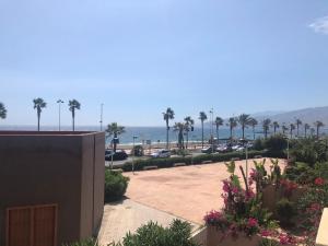 a view of a parking lot with palm trees and the ocean at Apart 3 EN PRIMERA LÍNEA DE PLAYA CON TERRAZA Y VISTAS AL MAR in Almería