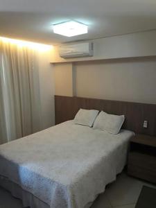 1 dormitorio con 1 cama con edredón blanco en Apto à beira-mar com wi-fi e piscina em Fortaleza, en Fortaleza