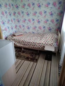 a small bed in a room with floral wallpaper at Sankt-Peterburg in Peresyp