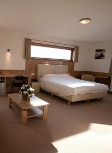 a bedroom with a large bed and a table with flowers at Hotel Chamdor in Roeselare