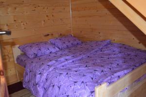 łóżko w drewnianej kabinie z fioletową pościelą w obiekcie Guest House Milena w mieście Žabljak