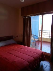 a bedroom with a red bed and a sliding glass door at Apartamento Piscina Playa Cedeira in Cedeira