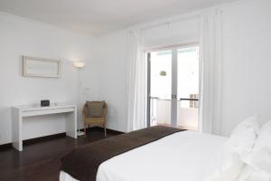 a white bedroom with a bed and a desk and a window at Remarkable view over Cascais Bay in Cascais