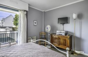 a bedroom with a bed and a tv and a balcony at Charmant appartement lumineux pour 4 personnes au Pouliguen in Le Pouliguen