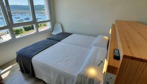 sypialnia z łóżkiem, komodą i oknami w obiekcie Apartamentos Costa da Morte Muxia w mieście Muxia