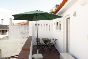 a patio with a table with a green umbrella at Cascais Downtown Apartment with Sea View in Cascais