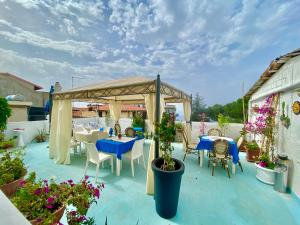eine Terrasse mit Tischen, Stühlen und einem Pavillon in der Unterkunft Hotel Scilla in Scilla