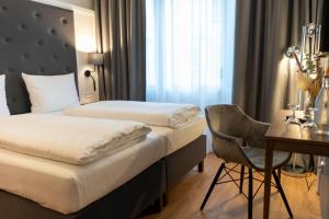 a hotel room with two beds and a desk at Signature Hotel Skarv in Elmshorn