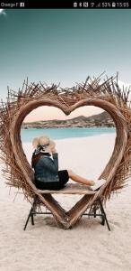 une femme assise sur une chaise en forme de cœur sur la plage dans l'établissement Appartement village Le Liberty 3 Argelès Sur Mer 2km plage, à Argelès-sur-Mer 3 autres photos