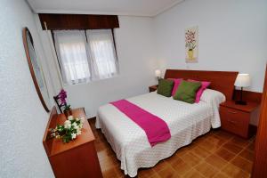 1 dormitorio con 1 cama con almohadas rosas y verdes en La Senda de la Playa, en Isla