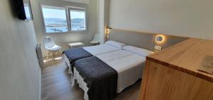 Apartamentos Costa da Morte Muxia في موتشيا: غرفة فندقية بسرير ونافذة كبيرة