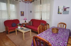 uma sala de estar com uma mesa e um sofá vermelho em Apartamento Playas de Quejo em Isla