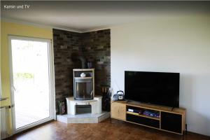 uma sala de estar com uma televisão de ecrã plano e uma parede de tijolos em Birkenblick Ferienwohnung Owwe em Rimbach