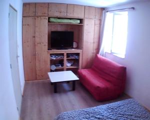 a living room with a red chair and a television at maison bleue in Belfort