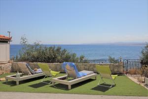 un grupo de sillas sentadas en el césped cerca del agua en Endless Blue Sea Frontal house, en Palaiokastro