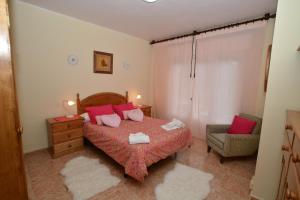 Un dormitorio con una cama con almohadas rojas y una silla en Villa Cancillo - 6802, en Noja