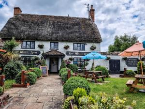 a cottage inn with tables and umbrellas in front of it at The White Hart, Wroughton in Swindon