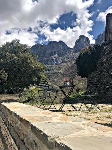 two benches sitting on a wall with mountains in the background at Konaki Hotel in Papingo