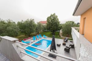 a swimming pool with chairs and umbrellas on a balcony at Apartment Danica in Poličnik