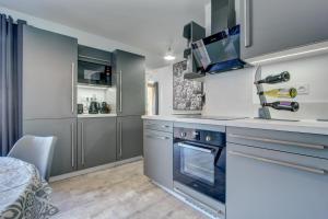 a kitchen with gray cabinets and a stove top oven at Bailicîmes Apartment - Snow and Trek - Morzine in Morzine