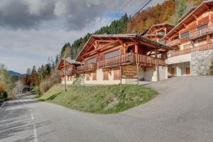 モルジヌにあるRose et Chardon Apartment - Snow and Trek - Morzineの道路横の丘の上の大きな木造建築