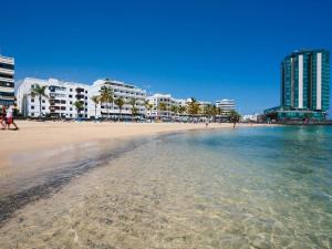 a beach with buildings and people walking in the water at Casa Fife in Arrecife