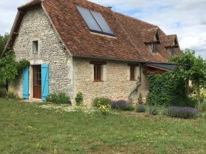uma casa de pedra com uma porta azul num quintal em Le Chant du Coq em Lacave