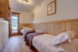 2 camas en una habitación con paneles de madera en Apt Le Croix - 3 bedroom with hot tub - Snow and Trek, en Morzine