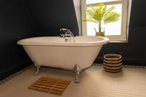 Langleigh Villa في إلفراكومب: حوض استحمام أبيض في حمام مع نافذة