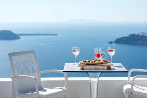 a table with a glass of wine and a plate of food at Kasimatis by La Perla - Adults Only in Imerovigli