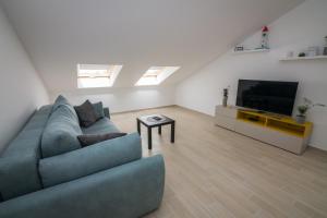 ein Wohnzimmer mit einem blauen Sofa und einem Flachbild-TV in der Unterkunft Apartment Skylight in Kostrena