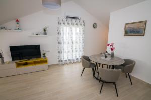 ein Wohnzimmer mit einem Tisch und Stühlen sowie einem TV in der Unterkunft Apartment Skylight in Kostrena