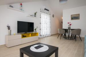 ein Wohnzimmer mit einem TV und einem Tisch in der Unterkunft Apartment Skylight in Kostrena