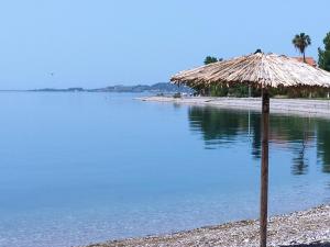 a straw umbrella on a beach next to the water at Nafpaktos beach Apartment in Nafpaktos