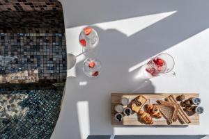 einen Tisch mit einem Tablett mit Speisen und Gläsern Wein in der Unterkunft Kasimatis by La Perla - Adults Only in Imerovigli