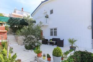 une terrasse avec des plantes en pot et une maison blanche dans l'établissement Apartman Mavarcica A4, à Trogir