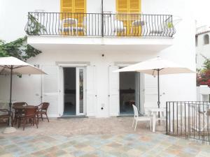 Un edificio blanco con mesas, sillas y sombrillas. en GRomano Apartments, en Isquia