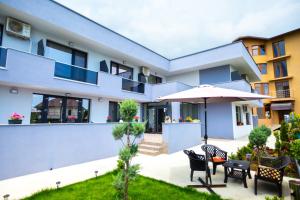 a house with a patio with chairs and an umbrella at Casa Angy in Techirghiol