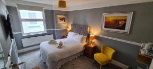 niewielka sypialnia z łóżkiem i żółtym krzesłem w obiekcie Sunnycroft Private Hotel w mieście Llandudno