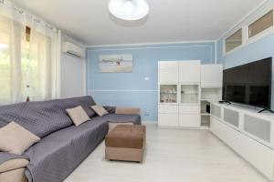 Dormitorio azul con sofá y TV en My Desenzano Holiday Apartment en Desenzano del Garda