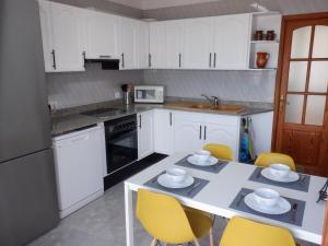 una cocina con armarios blancos y una mesa con sillas amarillas en Jormar en Port de Pollensa