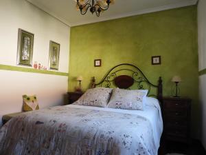 a bedroom with a bed with white sheets and green walls at Tranquilidad en helguera in Helguera