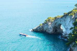 a boat in the water next to a cliff at Casa Colletta Vieste in Vieste
