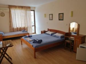 a bedroom with two beds and a desk and a window at Guest House "Zora - Sarafovo" in Burgas