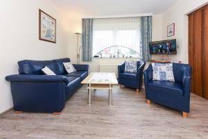 een woonkamer met twee blauwe banken en een tafel bij Ferienwohnung An Bord in Bensersiel