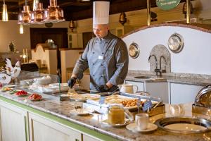a chef preparing food on a counter in a kitchen at CESTA GRAND Aktivhotel & Spa in Bad Gastein